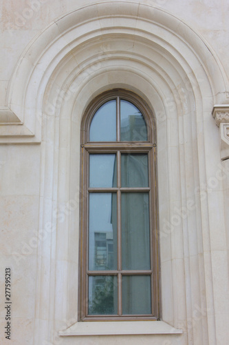 Wooden window on church facade close up view. Simple architecture detail of single window on beige facade wall 