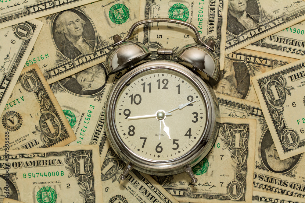 Alarm clock on carpet of dollar bills, time is money. Alarm clock on carpet of dollar bills, time is money.
