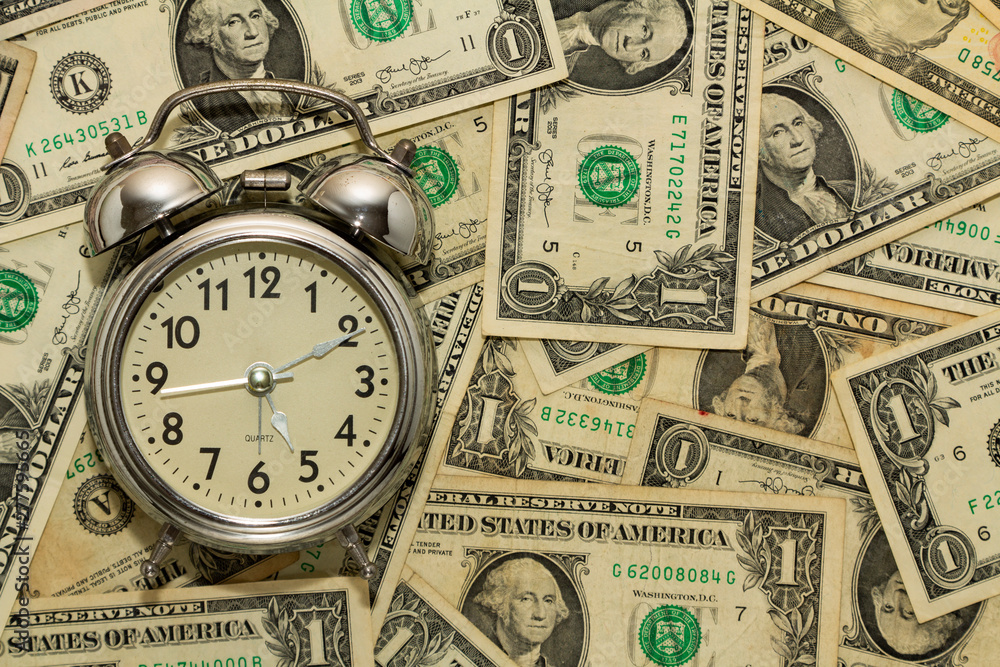 Alarm clock on carpet of dollar bills, time is money. Alarm clock on carpet of dollar bills, time is money.