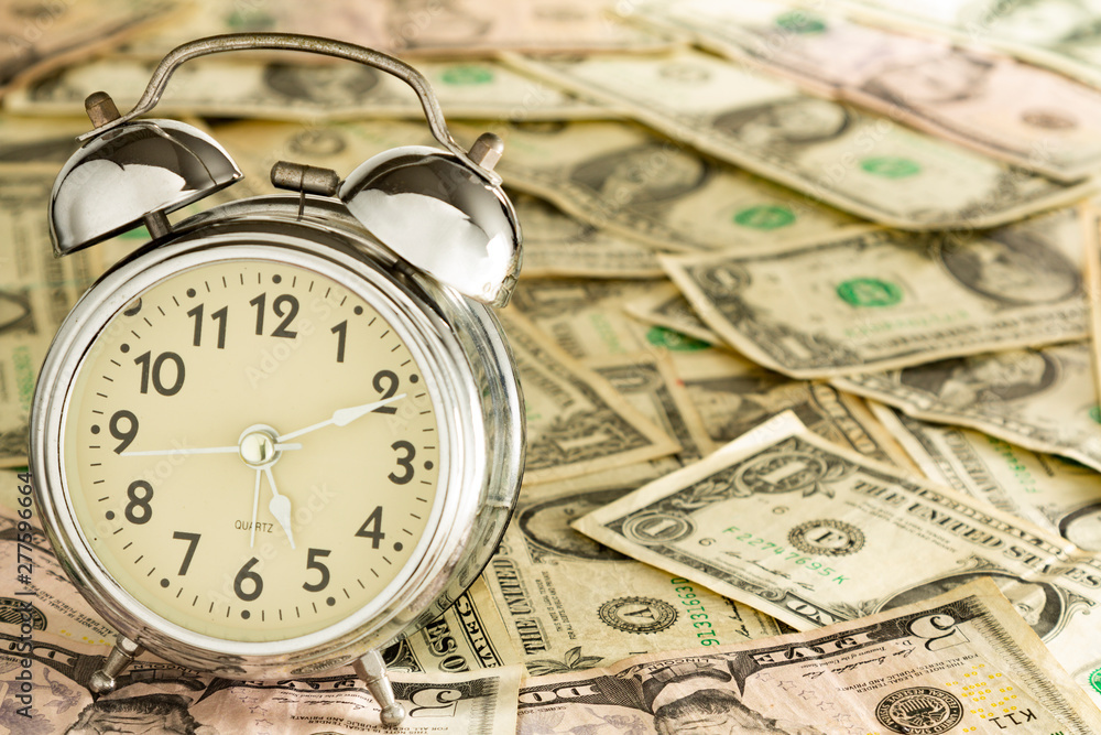 Alarm clock on carpet of dollar bills, time is money. Alarm clock on carpet of dollar bills, time is money.