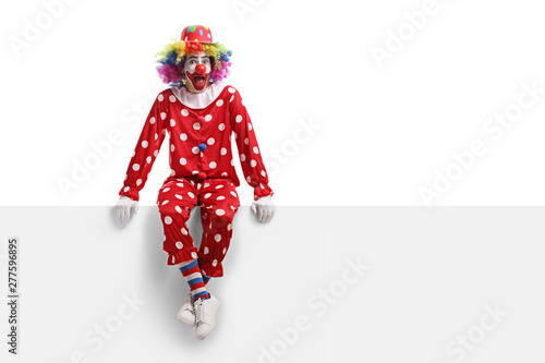 Schilderij op canvas Surprised clown sitting on a white billboard