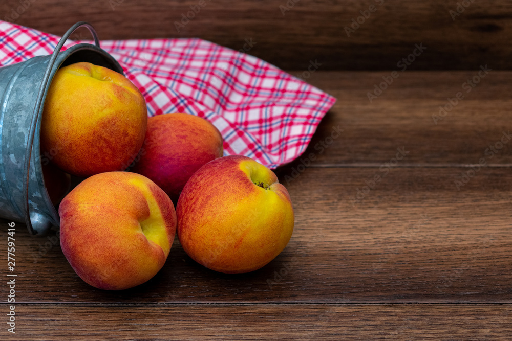 Peaches in a bucket with picnic tabletop over wooden background with copy space DSC-1070 2