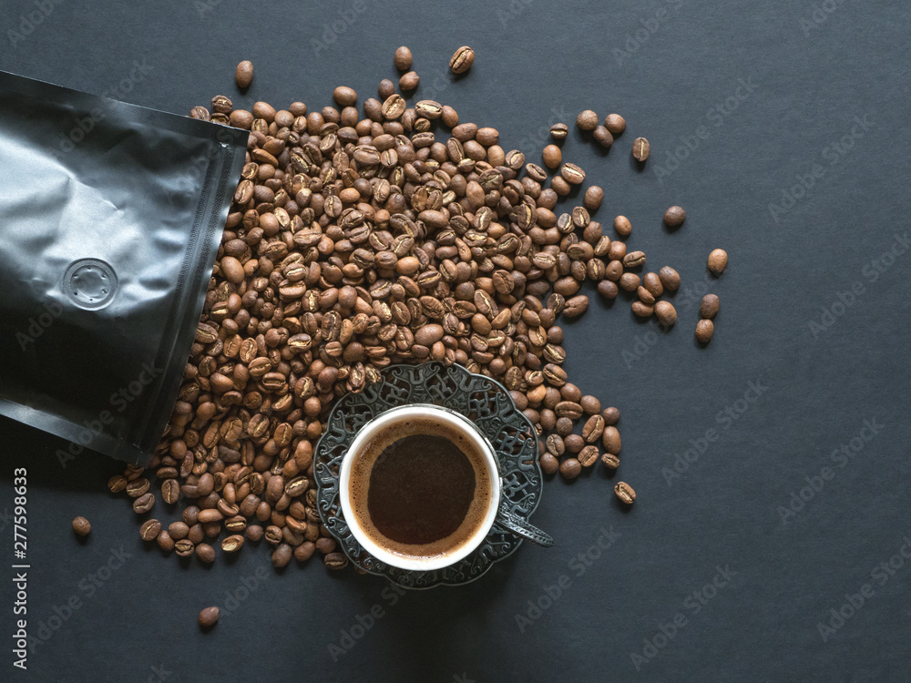 Coffee beans spilled from a package on black table Coffee beans spilled from a package on black table