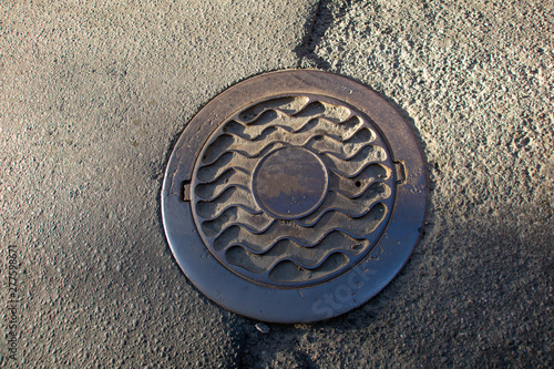 Sewer manhole on the urban asphalt road. Closeup photo photo