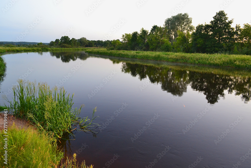 River landscape on a summer evening in Belarus, river Schara at Slonim village. Summer nature river landscape. Picturesque nature, rural river landscape