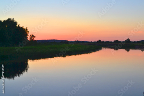 Belarus landscape. Sunset in a river landscape creating dark silhouette of the scenery  sundown painting the sky and clouds in beautiful colors.