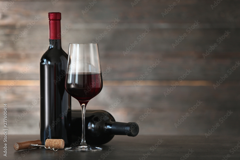 Composition with glass and bottles of red wine on table. Space for text
