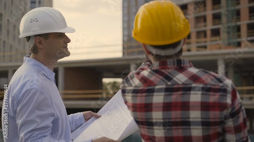 Apartment plumbing system and professional jobs, plumber and engineer talking and looking at building plans in construction site. Steadicam shot 4K