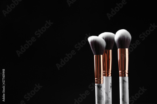 Set of makeup brushes against dark background. Space for text