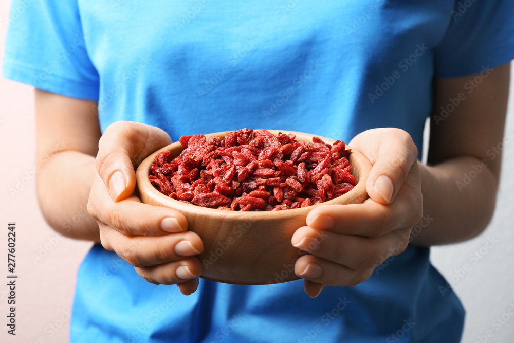 Woman holding bowl of red dried goji berries, closeup Woman holding bowl of red dried goji berries, closeup