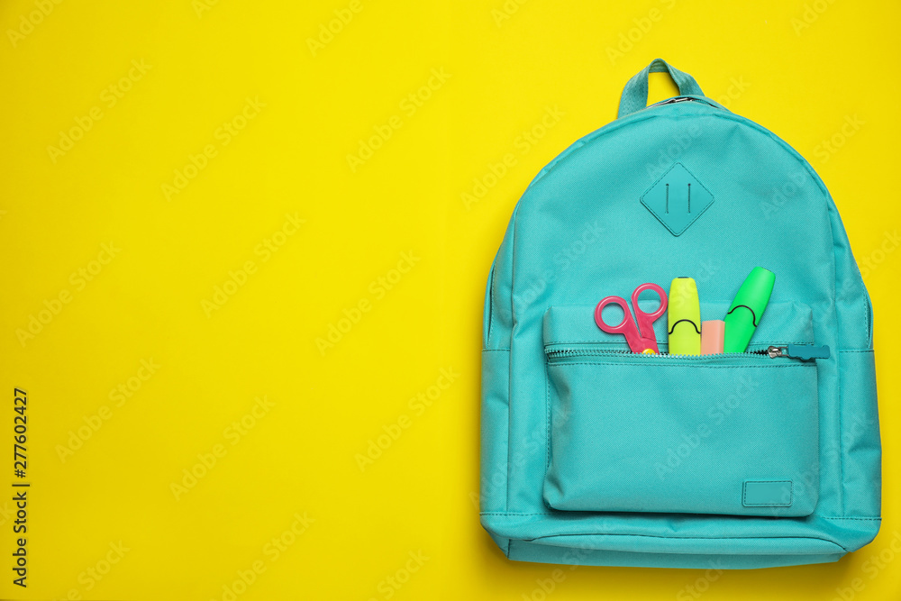 Stylish backpack with different school stationary on yellow background, top view. Space for text - obrazy, fototapety, plakaty 