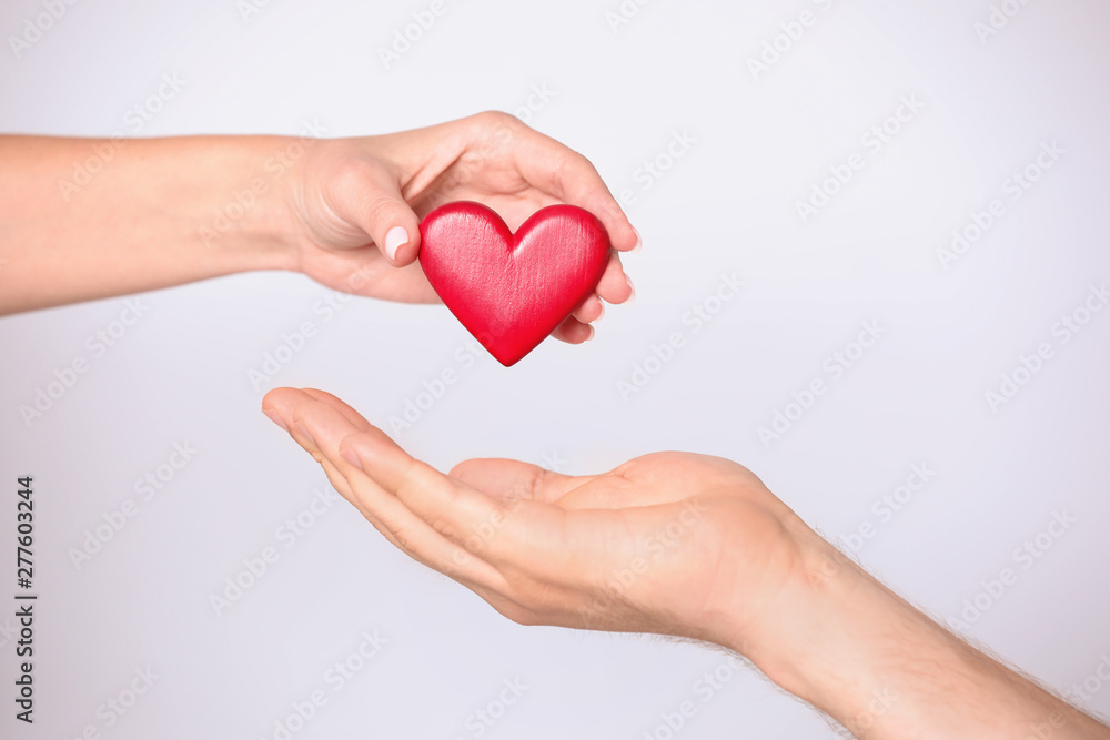 Woman giving red heart to man on white background, closeup. Donation concept Woman giving red heart to man on white background, closeup. Donation concept