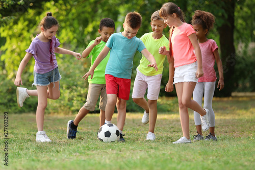 Cute little children playing with soccer ball in park