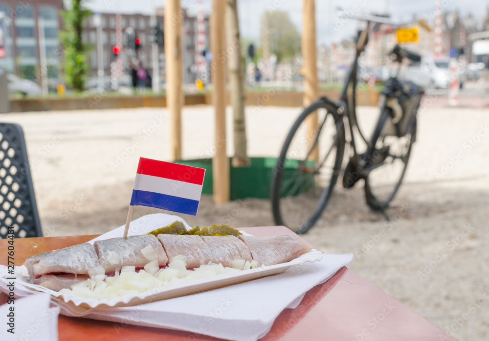 Slised herring with flag of Netherlands. Onion and cucumber. Bicycle on the background.