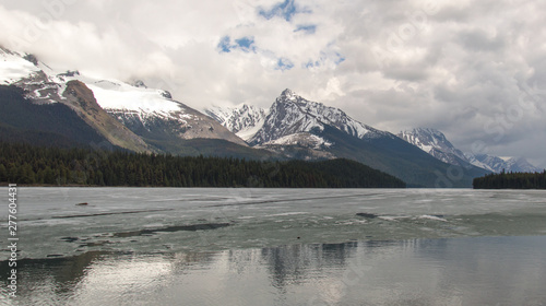 Cloudy Rocky mountains in British Columbia reflecting in the icy water