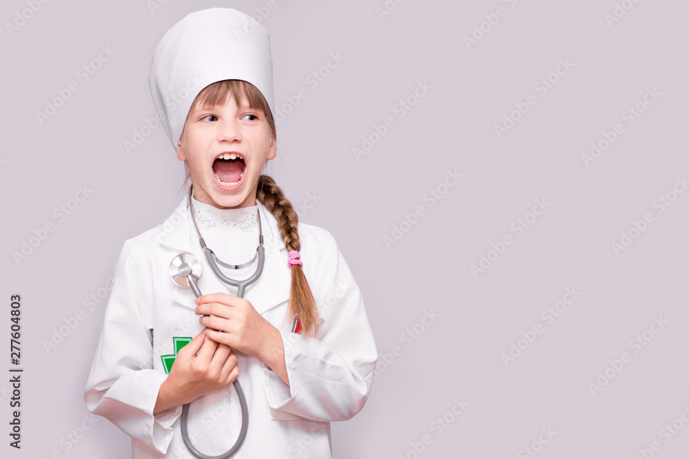 Smiling little girl in medical uniform holding stethoscope and looking at camera isolated on white. Smiling little girl in medical uniform holding stethoscope and looking at camera isolated on white.