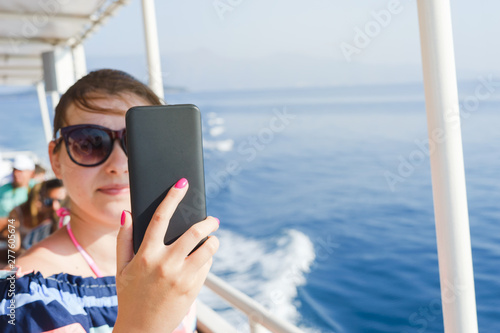 Young woman taking self portrait pictures while sailing on the ship on the sea summer holiday vacation © Miljan Živković