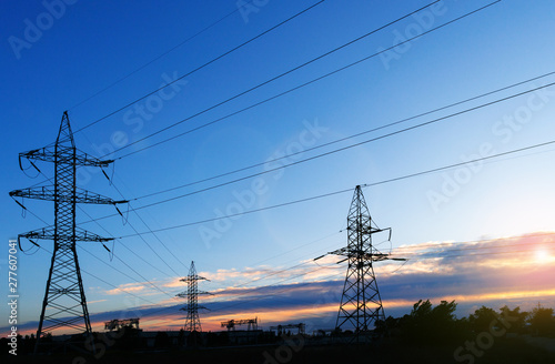 A silhouette of high voltage power lines against a colorful sky at sunrise.