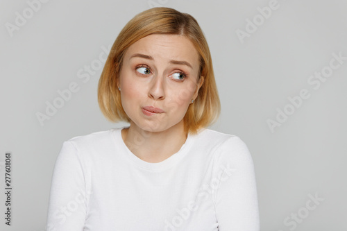Oops I did it again speechless feel, how awkward! Close up studio portrait of shy awkward young woman biting lips feeling embarrassed, confused and nervous, looking aside, isolated on grey background. photo