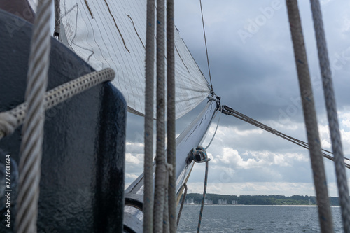 View along the main boom with rigging, gaffel sail and pulley blocks of a historical sailing ship  photo