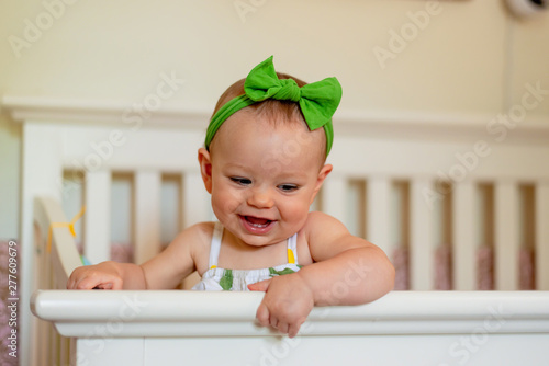 Happy baby girl standing in crib