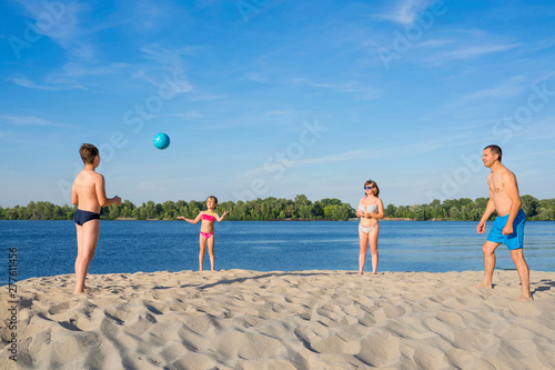 A family on the river bank playing with a ball. Summer season. Sports lifestyle.