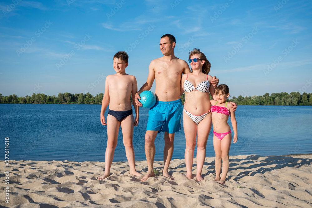 A happy family on the beach. People having fun on summer holidays. Father, mother and children against the blue river and sky. A happy family on the beach. People having fun on summer holidays. Father, mother and children against the blue river and sky.