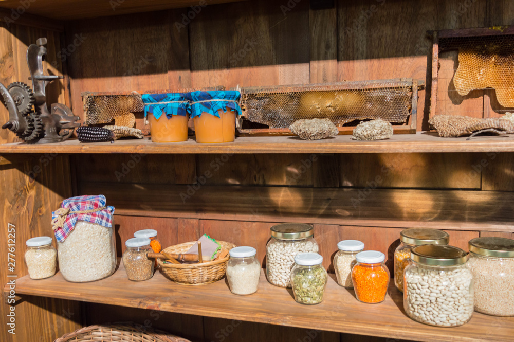 Shelves with jars of seeds and jars of honey next to honeycombs.