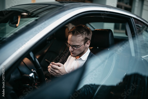 Male car driver uses a smartphone for business.