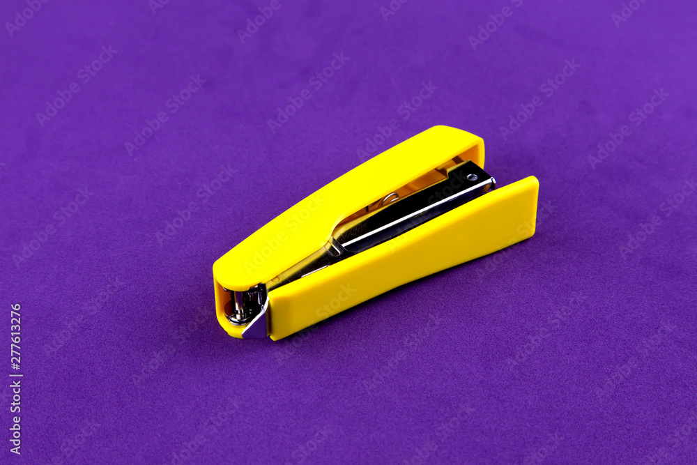 School stationery yellow stapler isolated on purple background close up School stationery yellow stapler isolated on purple background close up