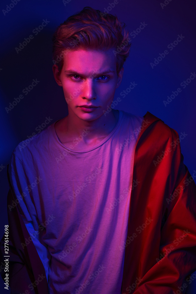 Fototapeta premium Fashion photo portrait of a young male model trendy fashionable urban style in studio on color gel background
