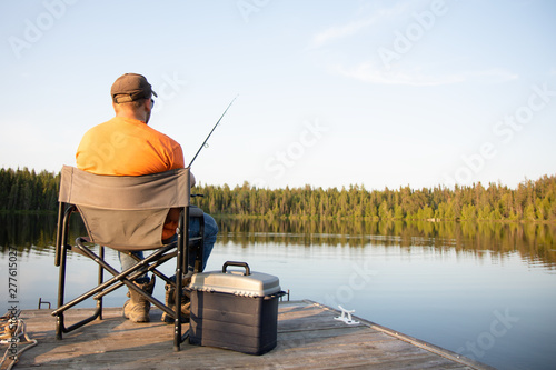 Fotografia A man fishing on a lake on a wooden dock in Ontario Canada