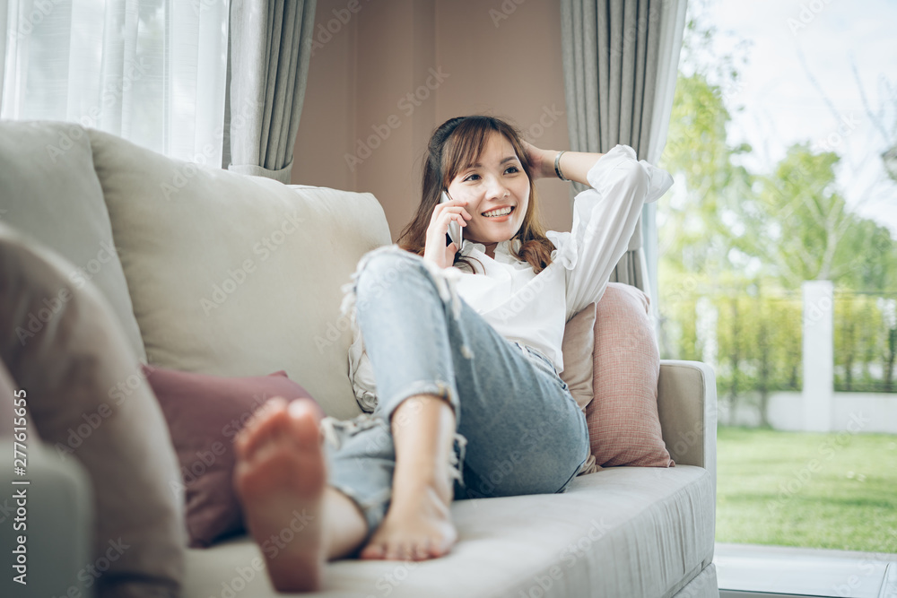 Asian woman sitting on the couch and talking on the phone Asian woman sitting on the couch and talking on the phone