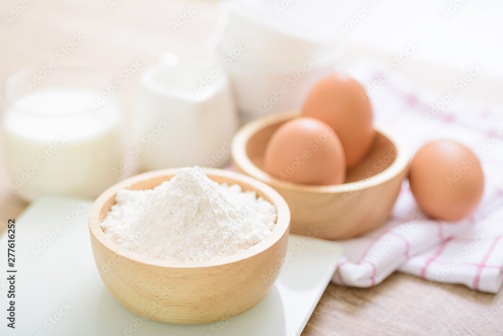 Eggs and flour prepared for baking, placed on a wooden table