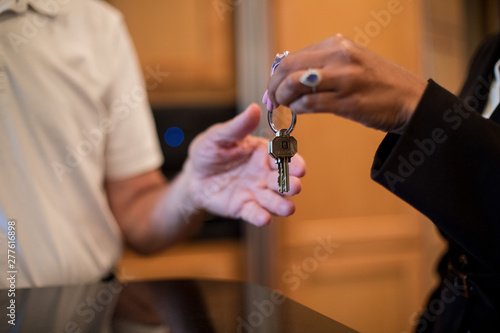 A female realtor hands over the keys to a new home to her client, an elderly man.