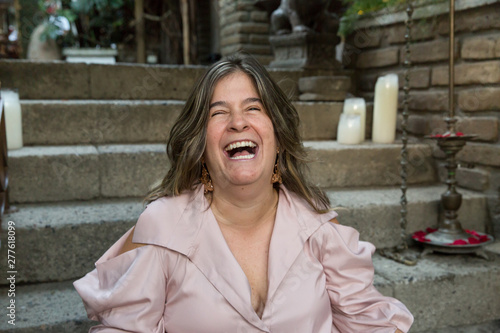 Konstfotografi Woman laughing outside with a beige blouse on a stair background