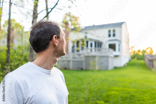 Young man homeowner in Herndon, Northern Virginia, Fairfax county residential neighborhood in spring or summer looking at house backyard