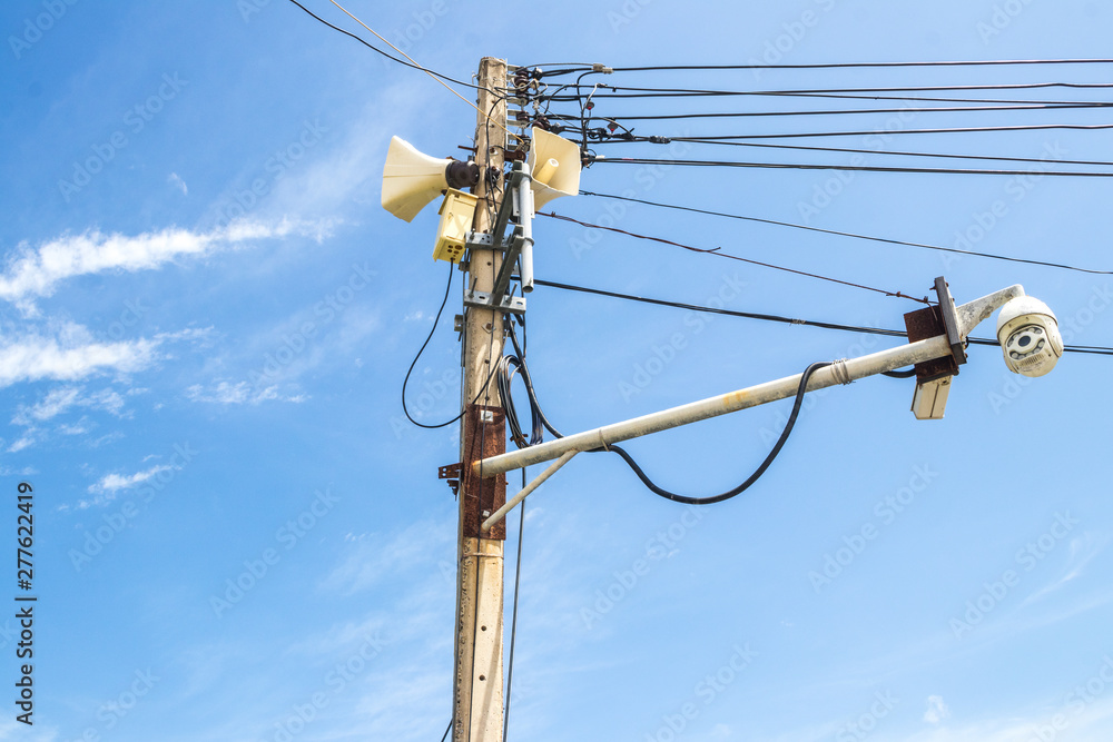 Horn speakers or Loudspeakers and old CCTV security camera on the electric pole in the urban area with blue sky background Horn speakers or Loudspeakers and old CCTV security camera on the electric pole in the urban area with blue sky background