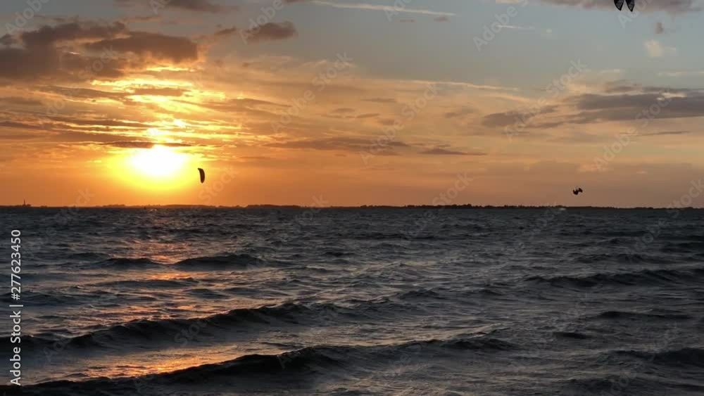 Kite surfing at sunset on the ocean with waves and jumps