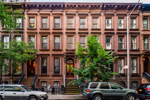 Scenic view of a classic Brooklyn brownstone block with a long facade and ornate stoop balustrades on a summer day in Clinton Hills, Brooklyn photo