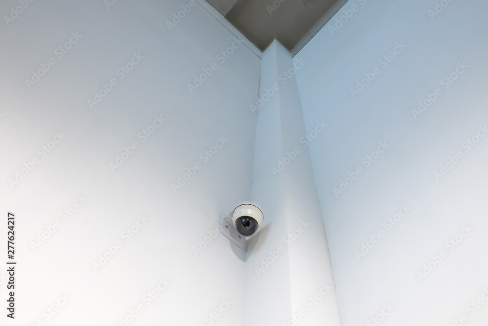 a security camera installed at the edge of a white wall.