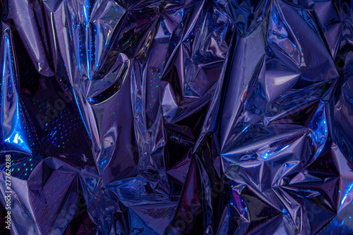 The background of crumpled holographic packaging film with an abstract pattern.