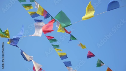 CLOSE UP: Colorful flags moving in the autumn breeze blowing over Swayambhunath. Multicolored prayer flags suspended from famous Monkey Temple flutter in the strong wind blowing across Kathmandu.
