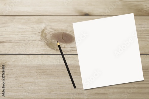 A blank white sheet with a black pencil on the table top view