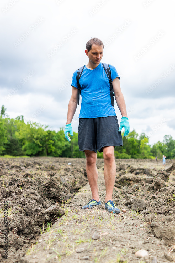 Fototapeta premium Man walking searching for minerals brown soil in Arkansas dirt landscape meadow field in Crater of Diamonds State Park