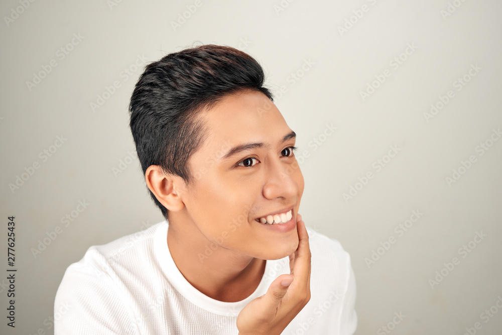 Portrait of shirtless young handsome Asian man checking his face for skin care and beauty concepts on white background Portrait of shirtless young handsome Asian man checking his face for skin care and beauty concepts on white background