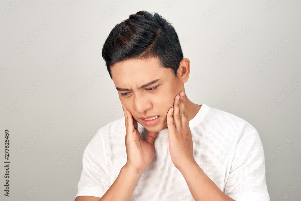 Portrait of Asian men with worry eyes use hand touching his cheek , feelings pain from toothache. Tooth and mouth disease concept. Portrait of Asian men with worry eyes use hand touching his cheek , feelings pain from toothache. Tooth and mouth disease concept.