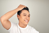 Happy handsome smiling Asian man touching his hair