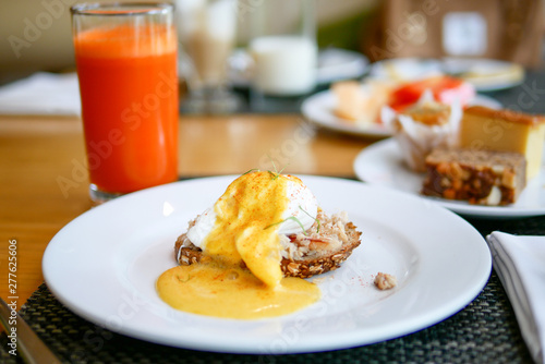 Delicious breakfast or morning food with eggs Benedict and and juice that placed on the wooden table