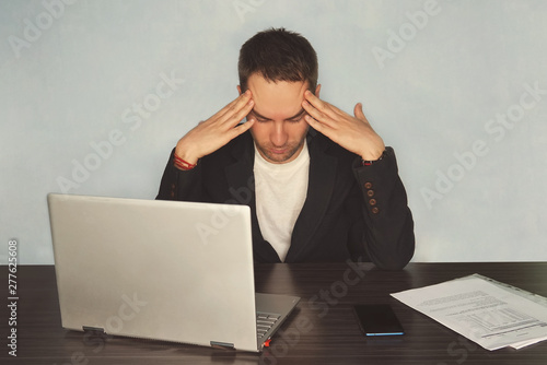 Serious frustrated businessman with closed eyes suffering from headache migraine at workplace, massaging temples, feeling tired exhausted, chronic work stress, tries to remember important information photo